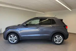 Profil côté gauche du Volkswagen T-Cross gris cendre 2025 en version 1.0 TSI 116 BVM6 VW EDITION, intérieur showroom.