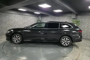Vue latérale droite d'une Volkswagen Passat SW noire 2024 en hybride essence, avec jantes alliage et vitres teintées.