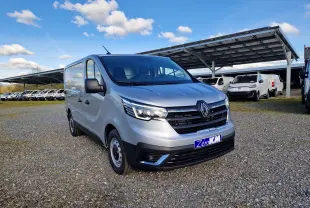 Renault Trafic Fourgon gris Highland vu en 3/4 avant droit sur parking avec plusieurs utilitaires en arrière-plan.