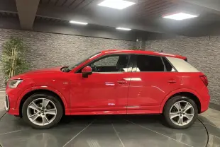 Audi Q2 S line rouge vue de profil côté gauche, toit et montant arrière blancs contrastants, jantes sport 5 branches.