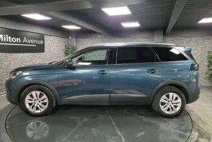 Profil côté gauche du Peugeot 5008 bleu métallisé 2019 avec jantes alliage et vitres surteintées en intérieur showroom.
