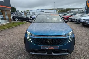 Vue avant d'un Peugeot 3008 GT bleu métallisé avec feux LED griffes et calandre noire laquée sous un ciel nuageux.