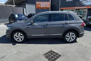 Profil côté gauche d'un Volkswagen Tiguan gris 2021 garé devant un garage avec jantes alliage 18 pouces.