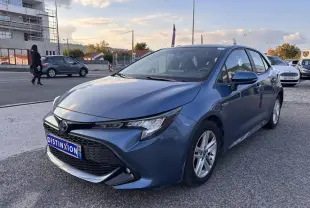 Toyota Corolla hybride bleu clair vue 3/4 avant droit avec calandre noire et jantes argentées.