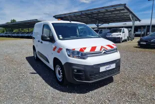 Citroën Berlingo blanc en 3/4 avant droit avec bandes rouges réfléchissantes et gyrophare orange sur le toit.