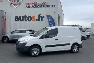 Vue de profil côté gauche d'un utilitaire Citroën Berlingo blanc stationné devant un garage autos.fr.