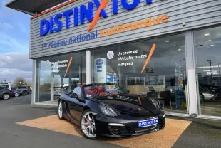 Porsche Boxster S noir intense vue 3/4 avant droit, capote ouverte et intérieur cuir rouge grenat visible.