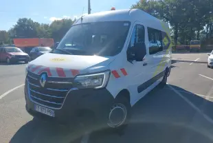 Renault Master blanc en 3/4 avant droit avec marquages rouges et jaunes et gyrophare sur le toit.