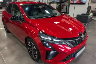 Renault Clio V ECO-100 CH TECHNO rouge flamme vue 3/4 avant droit en showroom avec détails LED avant.