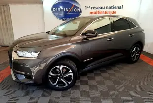 DS7 Crossback gris foncé en 3/4 avant droit, avec jantes alliage et feux LED dans un showroom intérieur.
