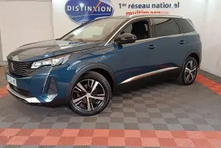 Peugeot 5008 bleu en 3/4 avant droit, avec jantes noires et détails chromés, sur sol damier intérieur showroom.