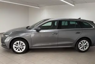 Skoda Octavia Combi 2023 gris graphite vue de profil côté gauche dans un intérieur neutre lumineux.