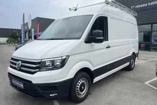 Fourgon Volkswagen Crafter blanc en 3/4 avant droit avec galerie de toit et jantes acier visibles sur parking.