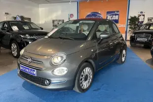 Fiat 500C gris vue 3/4 avant droit en intérieur avec phares allumés sur tapis bleu showroom.