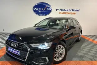 Audi A6 Avant noire vue en 3/4 avant droit avec phares allumés dans un showroom multimarque