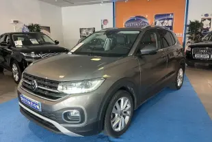 Volkswagen T-Cross gris Limestone métallisé vu de trois quarts avant droit en showroom avec éclairage intérieur.