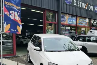 Vue 3/4 avant d'une Skoda Fabia blanche Cristal garée devant un garage avec calandre noire et feux LED.