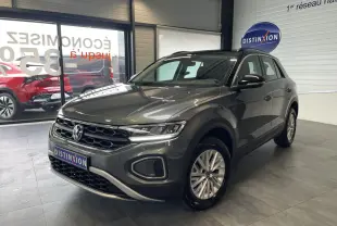 Volkswagen T-Roc 2025 gris Indium en 3/4 avant droit avec toit noir et jantes alliage 16 pouces dans un showroom.
