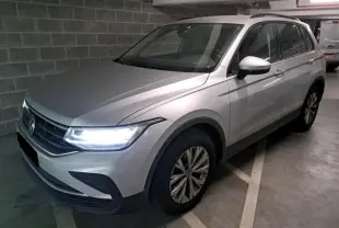 Volkswagen Tiguan 2.0 TDI 150 DSG7 Life argent fleuret en 3/4 avant droit avec feux LED allumés dans un parking.