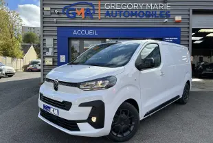 Fourgon Citroën Jumpy blanc en 3/4 avant droit, avec jantes noires et calandre moderne, devant un garage automobile.