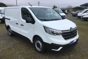 Vue 3/4 avant droit d’un fourgon Renault Trafic blanc 2025 avec calandre noire et feux LED distinctifs.