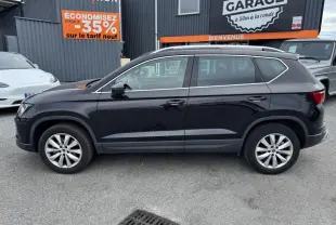 Profil côté gauche d'un SUV SEAT Ateca noir métallisé avec jantes alliage 17'' et barres de toit chromées.