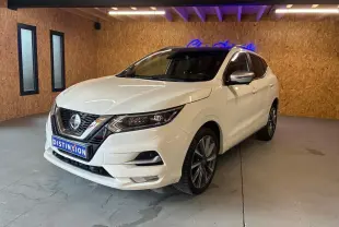 Nissan Qashqai blanc en 3/4 avant droit, intérieur visible noir, dans un showroom avec mur en bois et néon bleu.