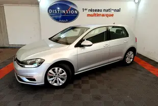 Volkswagen Golf 1.6 TDI gris clair vue 3/4 avant droit dans un showroom avec logo Distinxion en arrière-plan.