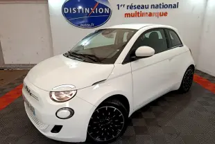 Fiat 500 électrique blanche vue 3/4 avant droit, avec phares allumés et jantes noires stylisées.