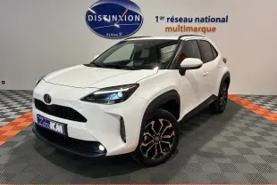 Toyota Yaris Cross blanc en 3/4 avant droit, avec jantes noires et phares LED allumés en showroom.