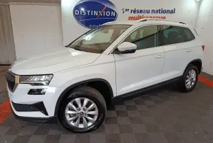 Vue 3/4 avant droite d'un Skoda Karoq blanc 2024 avec jantes alliage et barres de toit noires en showroom