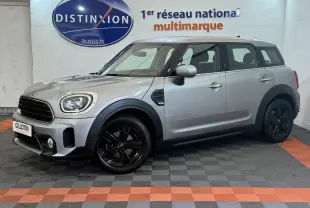 Vue de profil droit d'une MINI Countryman Cooper Essential gris clair avec jantes noires, stationnée en intérieur showroom.