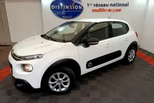 Citroën C3 blanche vue 3/4 avant droit, avec protections latérales noires et jantes alliage en intérieur showroom.