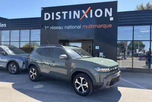 Vue 3/4 avant droite d'un Dacia Duster III hybride 2026 en kaki lichen avec jantes alliage diamantées devant un showroom Distinxion.