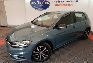 Volkswagen Golf bleu vue 3/4 avant droit, avec jantes noires et phares LED dans un showroom intérieur.