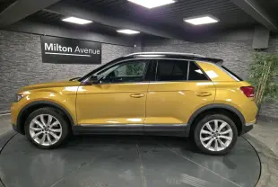 Volkswagen T-Roc jaune Curcuma vu de profil côté gauche avec toit noir et jantes alliage 18 pouces.