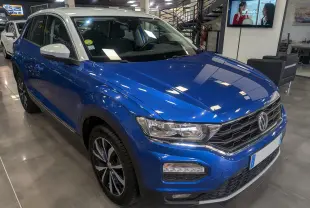 Volkswagen T-Roc bleu Ravenna avec toit blanc, vue 3/4 avant droit en showroom lumineux.