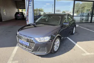 Audi A1 Sportback bleu firmament vue 3/4 avant droit, stationnée devant une vitrine avec plaque Distinxion.