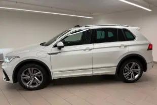 Profil droit d'un Volkswagen Tiguan blanc pur 2023 hybride rechargeable avec jantes R-Line distinctives en intérieur neutre.