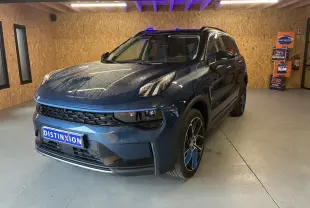 LYNK & CO 01 bleu en 3/4 avant droit, SUV hybride rechargeable avec jantes bicolores et toit noir dans un garage.
