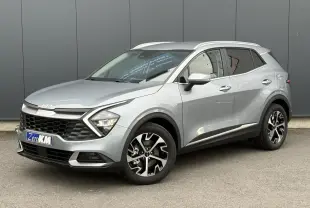 Kia Sportage gris perle en 3/4 avant droit, avec jantes alliage 18 pouces et calandre noire distinctive.