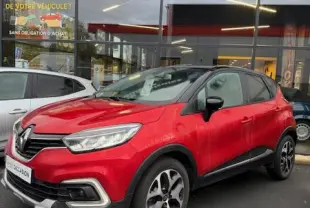 Renault Captur Intens rouge vue 3/4 avant droit, avec jantes alliage et calandre chromée visible devant un concessionnaire.
