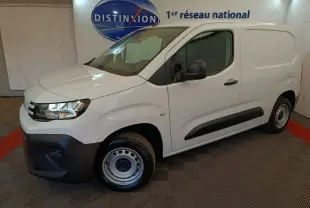 Vue 3/4 avant droit d’un Peugeot Partner blanc, version utilitaire avec protections noires et jantes acier, en intérieur showroom.