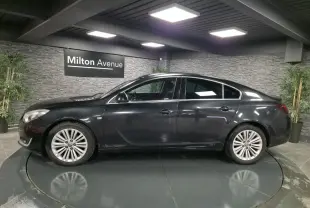 Profil côté gauche d'une berline Opel Insignia noire 2016 avec jantes alliage et vitres teintées en showroom.