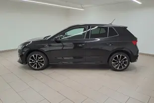 Profil côté gauche d'une Skoda Fabia 2024 noire Magic Nacré avec jantes alliage et finition Monte-Carlo dans un intérieur lumineux.