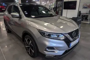Nissan Qashqai gris perle vu en 3/4 avant droit, avec jantes alliage bicolores et calandre chromée.