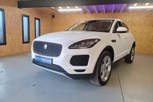 Jaguar E-PACE blanc vue 3/4 avant droit dans un garage avec calandre distinctive et phares LED allumés.