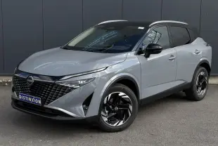 Nissan Qashqai gris Ceramic en 3/4 avant droit, avec calandre noire et jantes alliage 18 pouces distinctives.