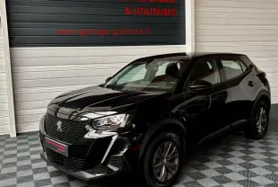 Peugeot 2008 noir vue 3/4 avant droit, avec calandre distinctive et phares LED dans un showroom.