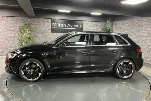 Profil côté gauche d'une Audi A3 1.4 TFSI e-tron S line noire avec jantes Audi Sport 18 pouces en intérieur showroom.